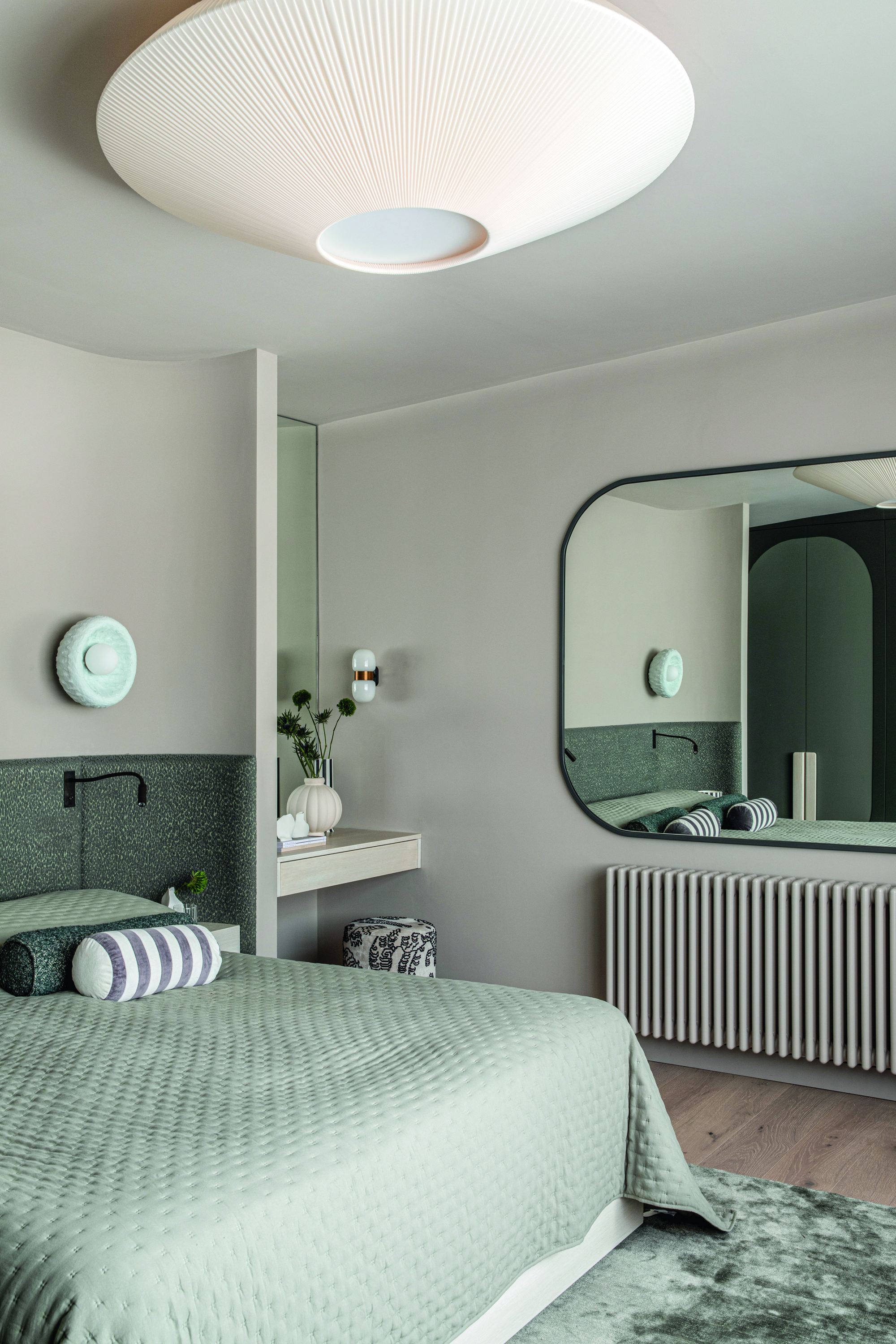 A bedroom with grey soft furnishings and headboard with an in-built vanity table