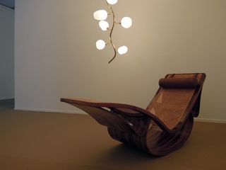 View of the wooden, cane and leather 'Rio' lounger by Oscar Niemeyer, 1978, and the brass and glass 'Vine' pendant light by Jeff Zimmerman