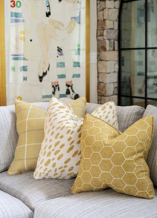 gray sofa with yellow patterned cushions, artwork in background