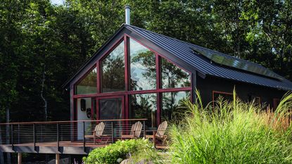 exterior of black-stained cedar holiday cabin with Adirondack chairs 