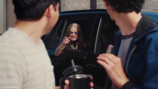 Ozzy Osbourne gesticulating at two yopung men from the window of his car