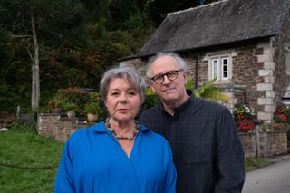 Anne Lloyd (Barbara Flynn) and Richard (Peter Davison) stand on the path outside her cottage, both facing the camera