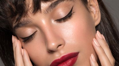 Close up studio shot of a beautiful woman with perfect skin, she touching her face