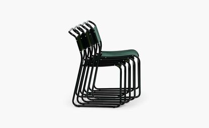 Stack of five black metal chairs with green seat and back
