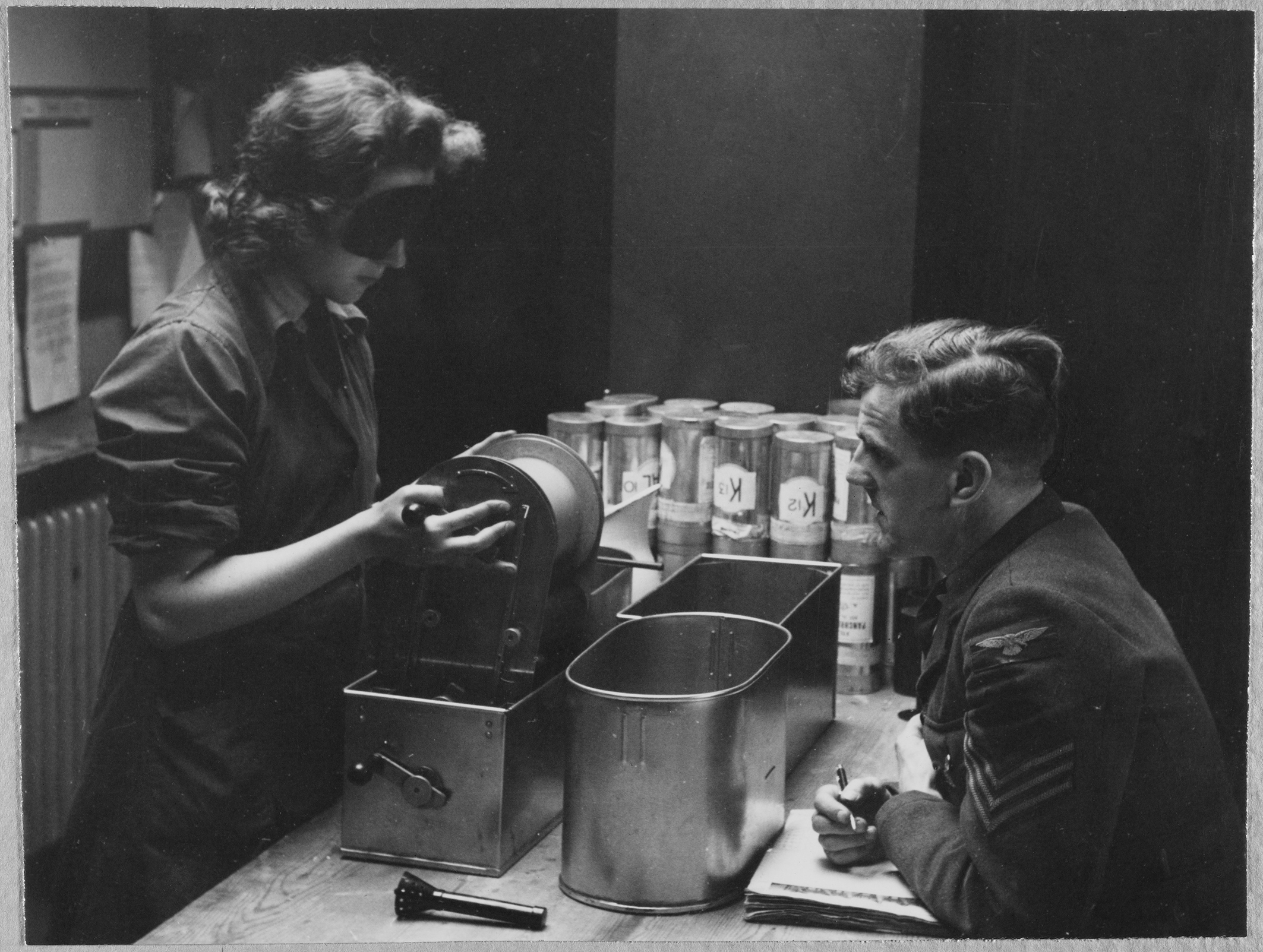 A Women's Auxiliary Air Force (WAAF) trainee handling a roll of photographic film whilst wearing an eye mask to simulate working in the dark, during the Trade Test Board examination at the end of the training course at the No.2 School of Photography in Blackpool