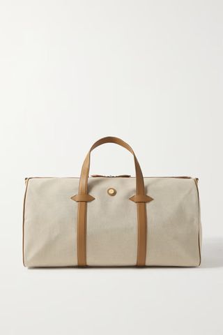 A large cream canvas weekender bag with brown leather handles