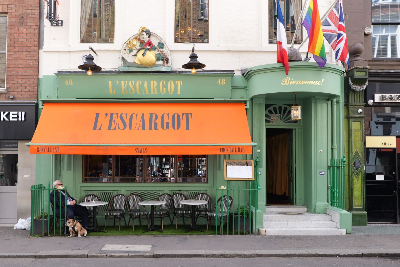 A restaurant with a green sign and tables and chairs outside