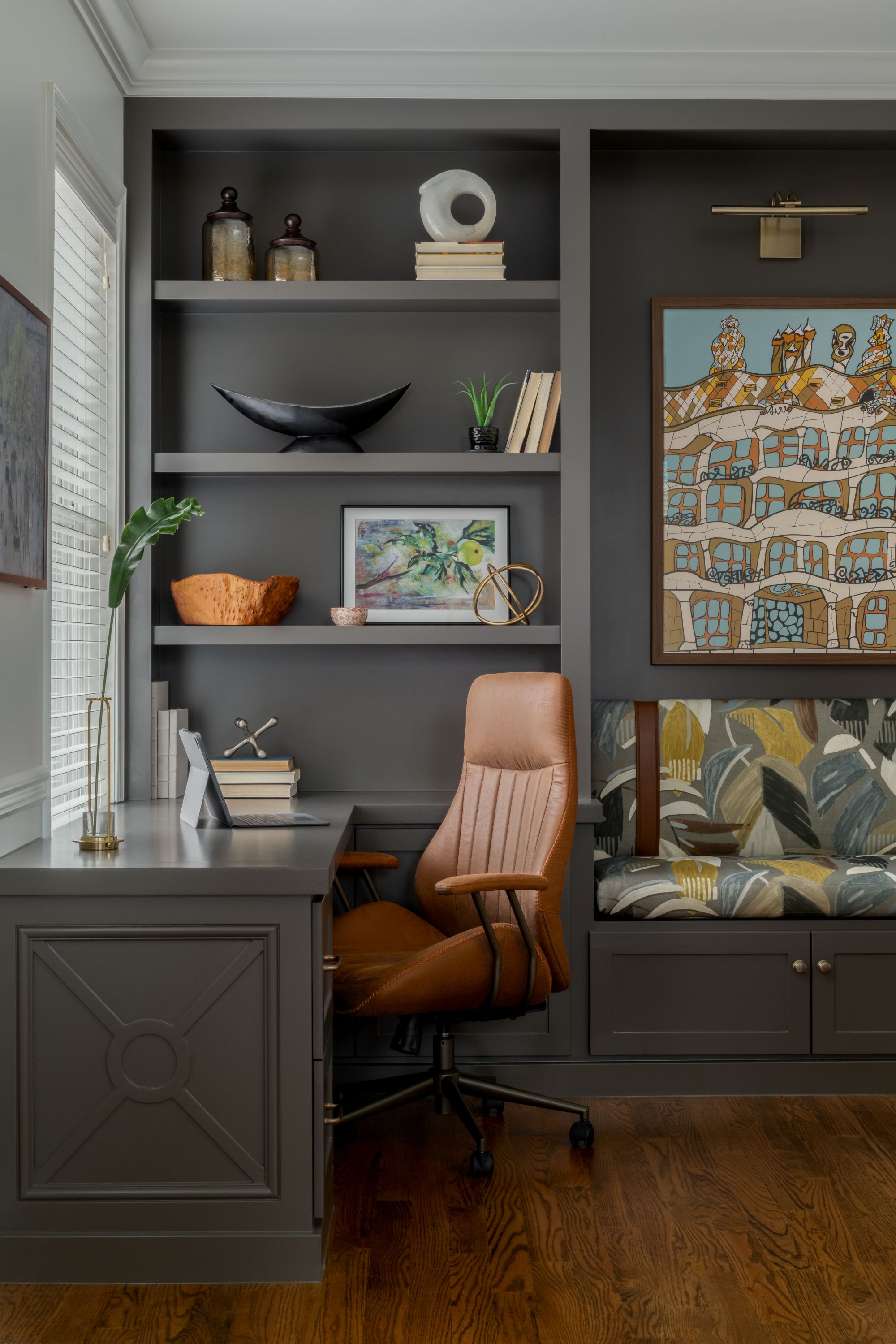an office space with gray built-in cabinets filled with miscellaneous objects and a brown swivel desk chair