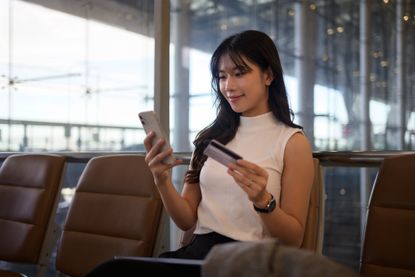 Young woman looking at airline miles credit cards at an airport