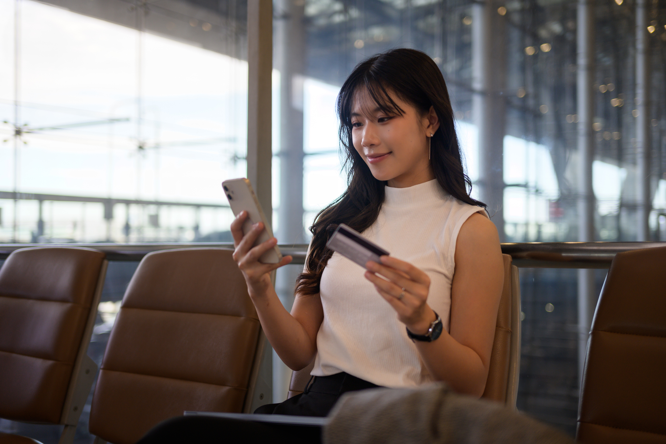 Young woman looking at airline miles credit cards at an airport