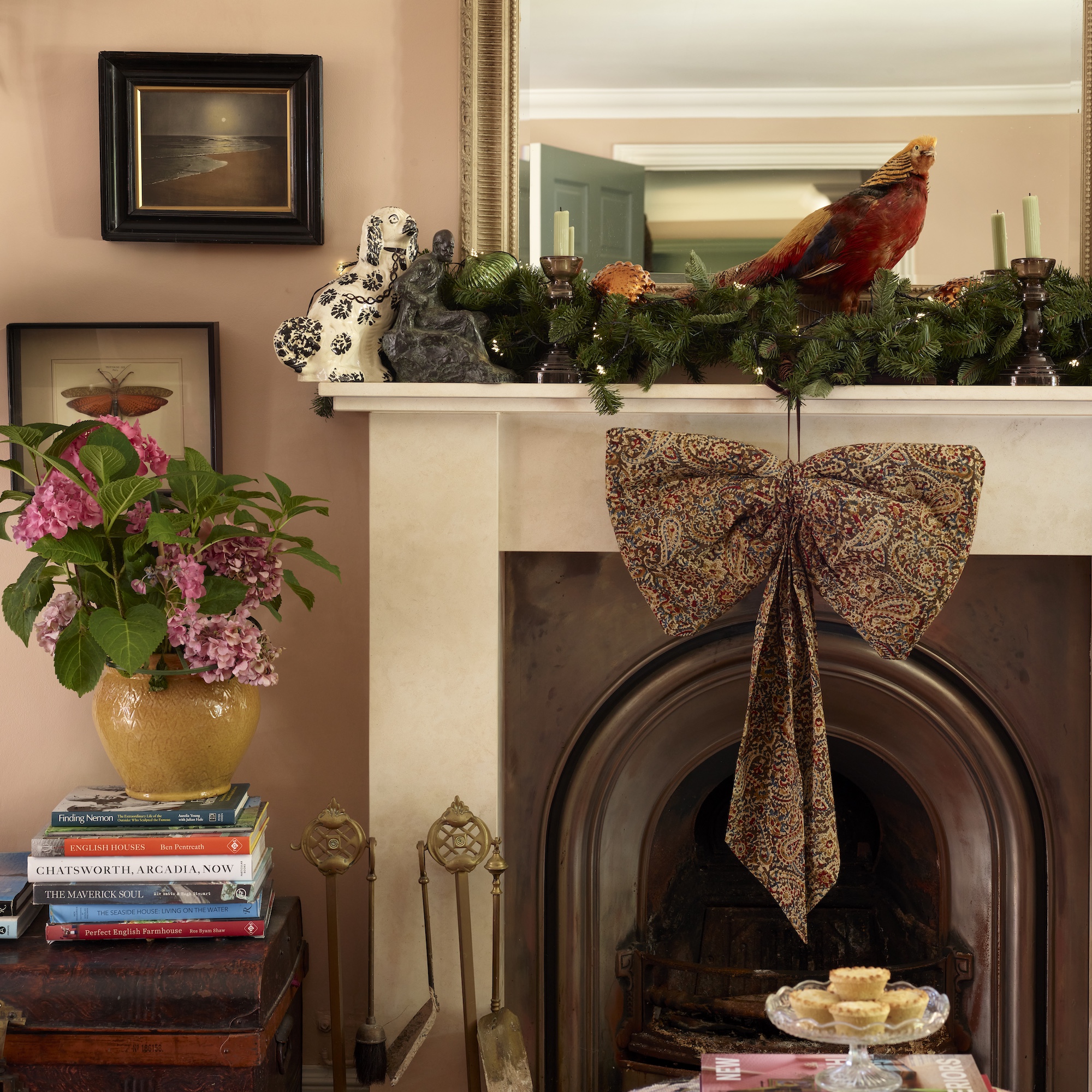 mantelpiece decorated for christmas with foliage, faux pheasant and large fabric bow