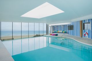 image of the indoor pool area at watergate bay, bright blue water and walls with glass doors viewing the sea
