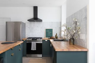 A green kitchen with white tiling and butcher block countertop