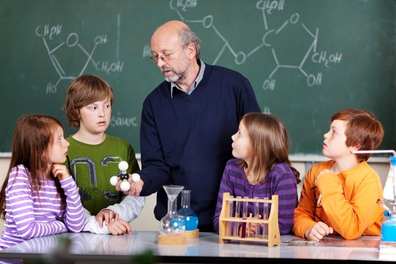 students in a chemistry class with teacher looking at models of molecules.