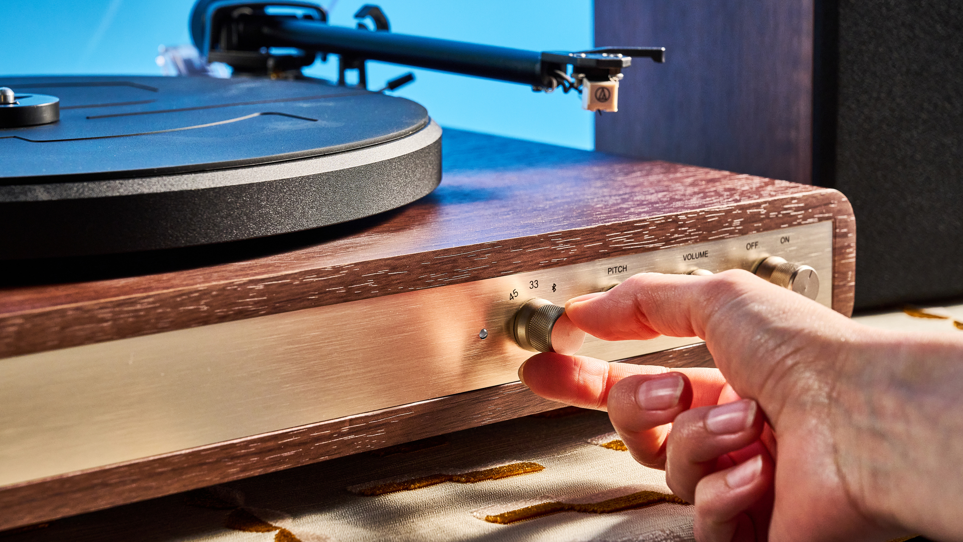 Crosley C65 turntable and bookshelf speakers photographed in front of a blue background on a brown table.