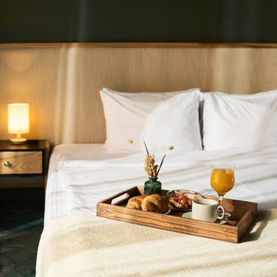 A tray of room service sitting on a bed in a nice hotel room.