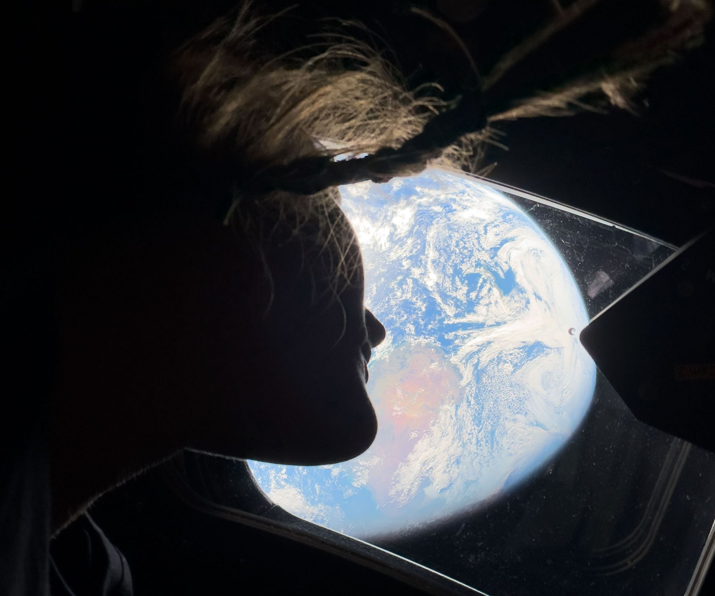 NASA astronaut and Artemis II mission specialist Christina Koch peers out of one of the Orion spacecraft's main cabin windows, looking back at Earth, as the crew travels towards the Moon on April 4, 2026.