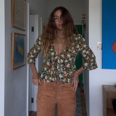 Angie wears a grey t-shirt, cream jumper, blue jeans