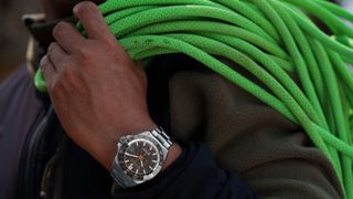 The Norqain Neverest GMT Glacier worn by a person carrying green ropes