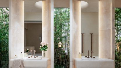 a his and hers sink in front of a glass wall with two backlit mirrors 