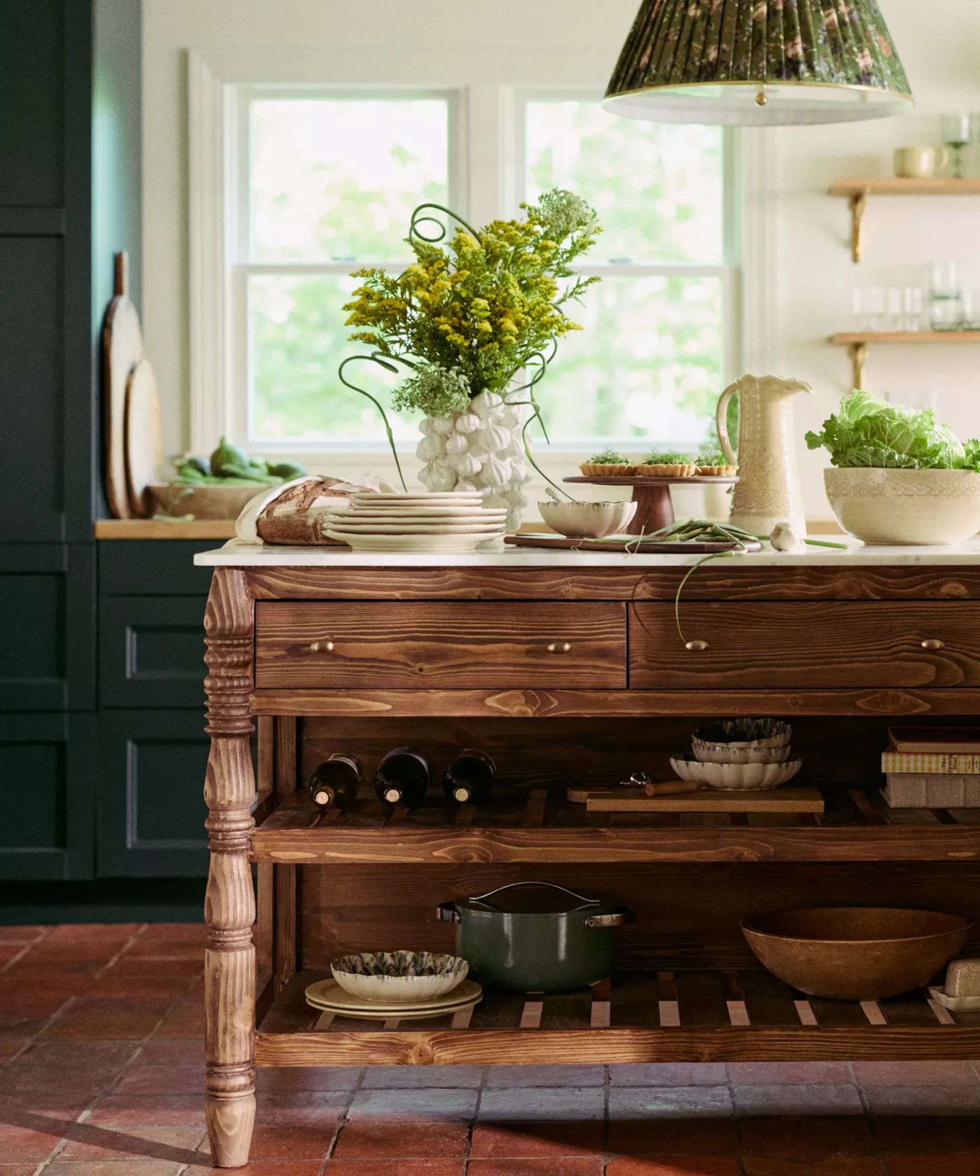 dark green kitchen with terracotta tiles and a wooden kitchen island styled for hosting