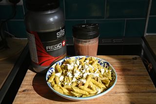 Bowl of pasta and a recovery protein shake on a kitchen worktop
