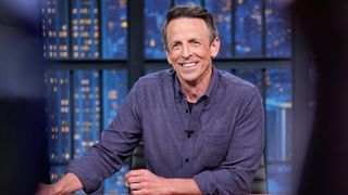 Seth Meyers wears a purple shirt and speaks while sitting at his desk on Late Night with Seth Meyers 2026.