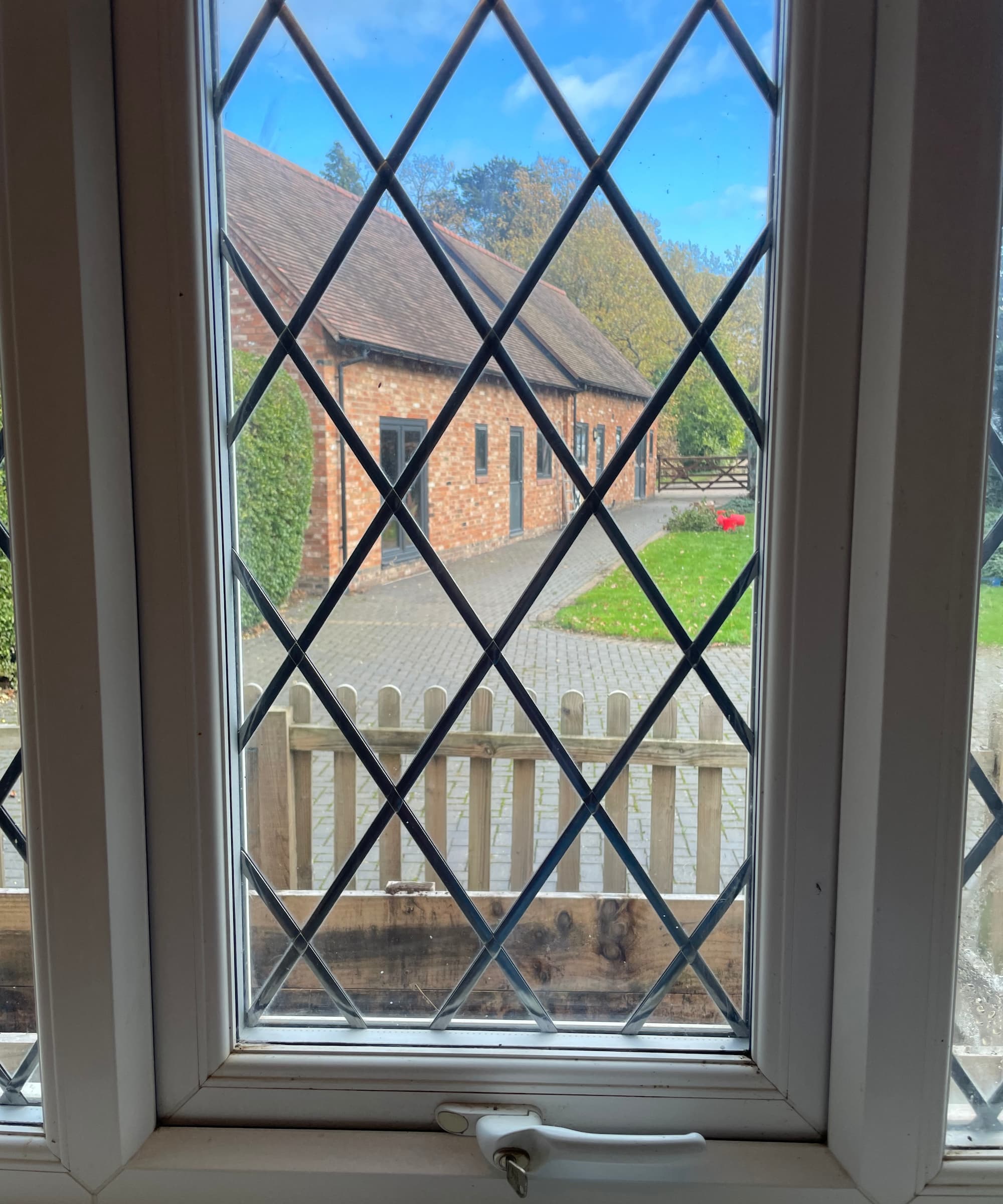 A closed uPVC window looking out onto a back garden