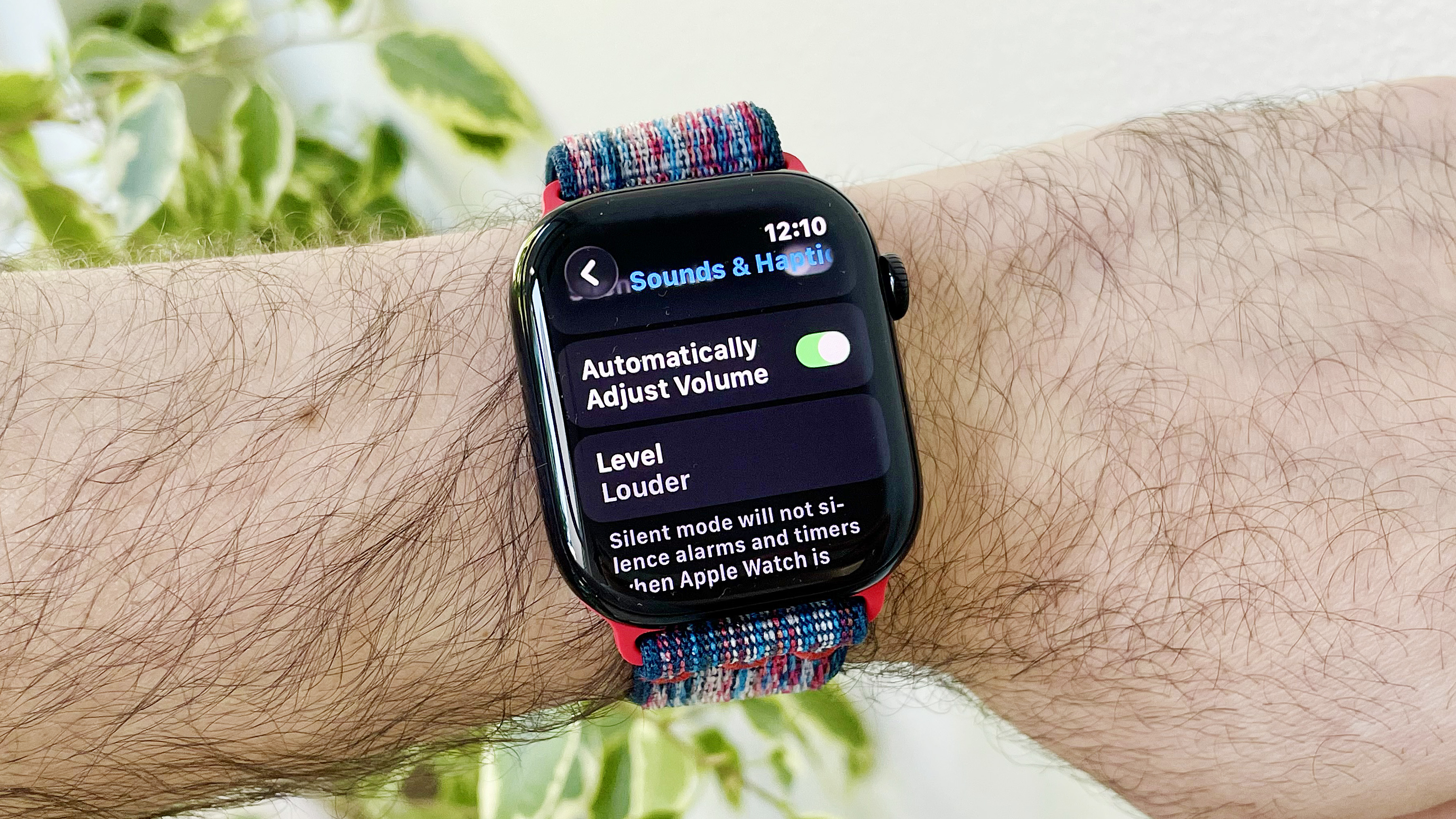 Close-up of a user's wrist wearing the Apple Watch Series 10 running the latest watchOS 26 software. The screen shows the new Automatic Audio Adjustments setting