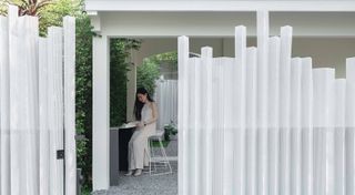 entrance behind fence with woman inside at InJoy Snow Hotel Bangkok by HAS design and research in bangkok