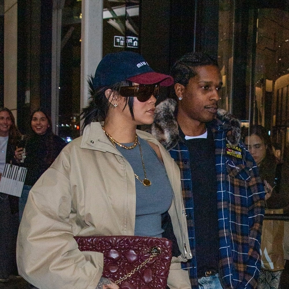 Rihanna wearing a two-toned Miu Miu baseball cap, gray tank top, black belt, black pants, burgundy Dior bag