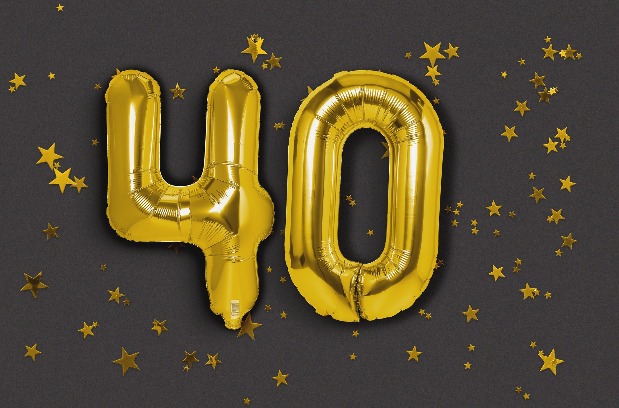 Gold balloons as the number 40 on a dark background littered with gold stars