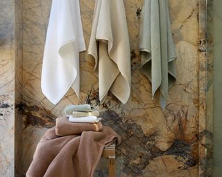 Parachute Organic Plush Bath Collection towels hanging in a marble-walled bathroom.