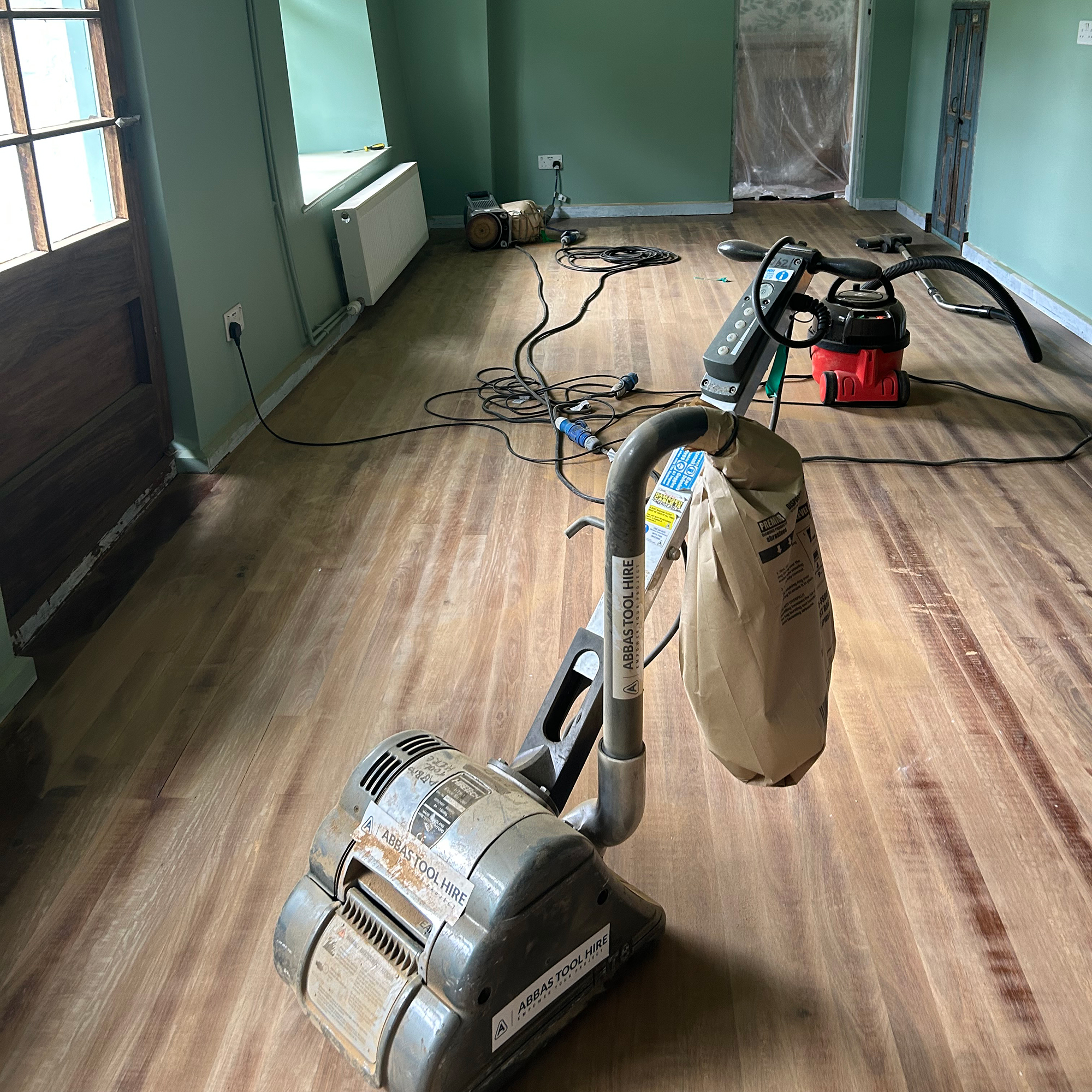 Sander and Henry Hoover on wooden floor in room with green walls