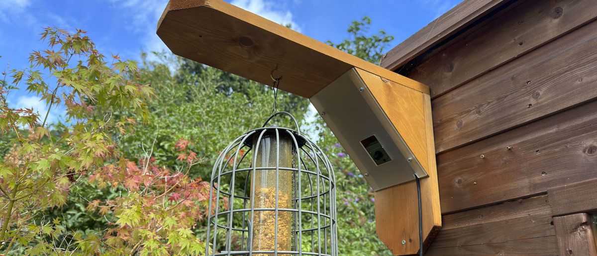 Green Feathers Bird Feeder Camera attached to a shed