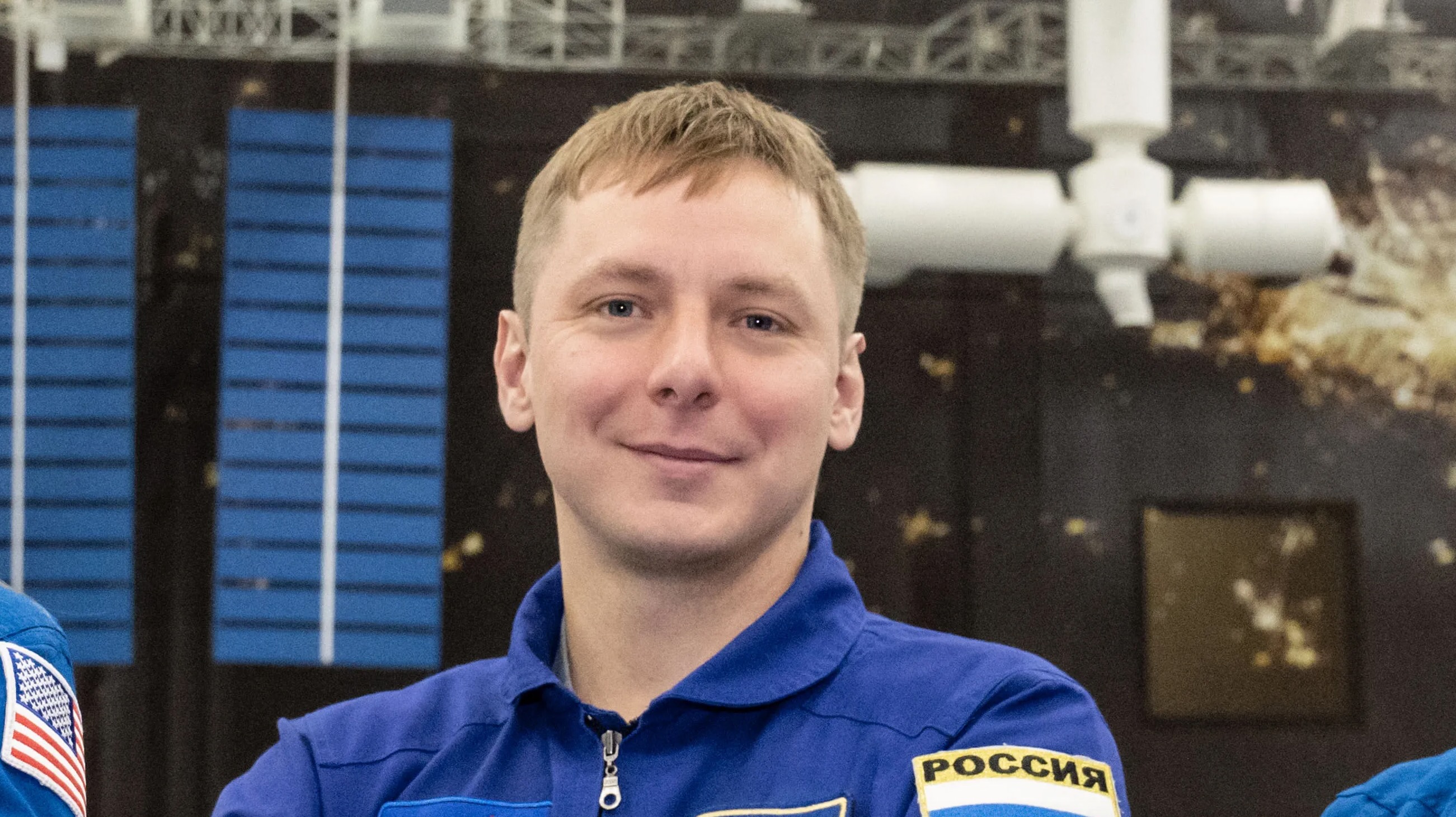 closeup of a smiling young man wearing a blue flight suit