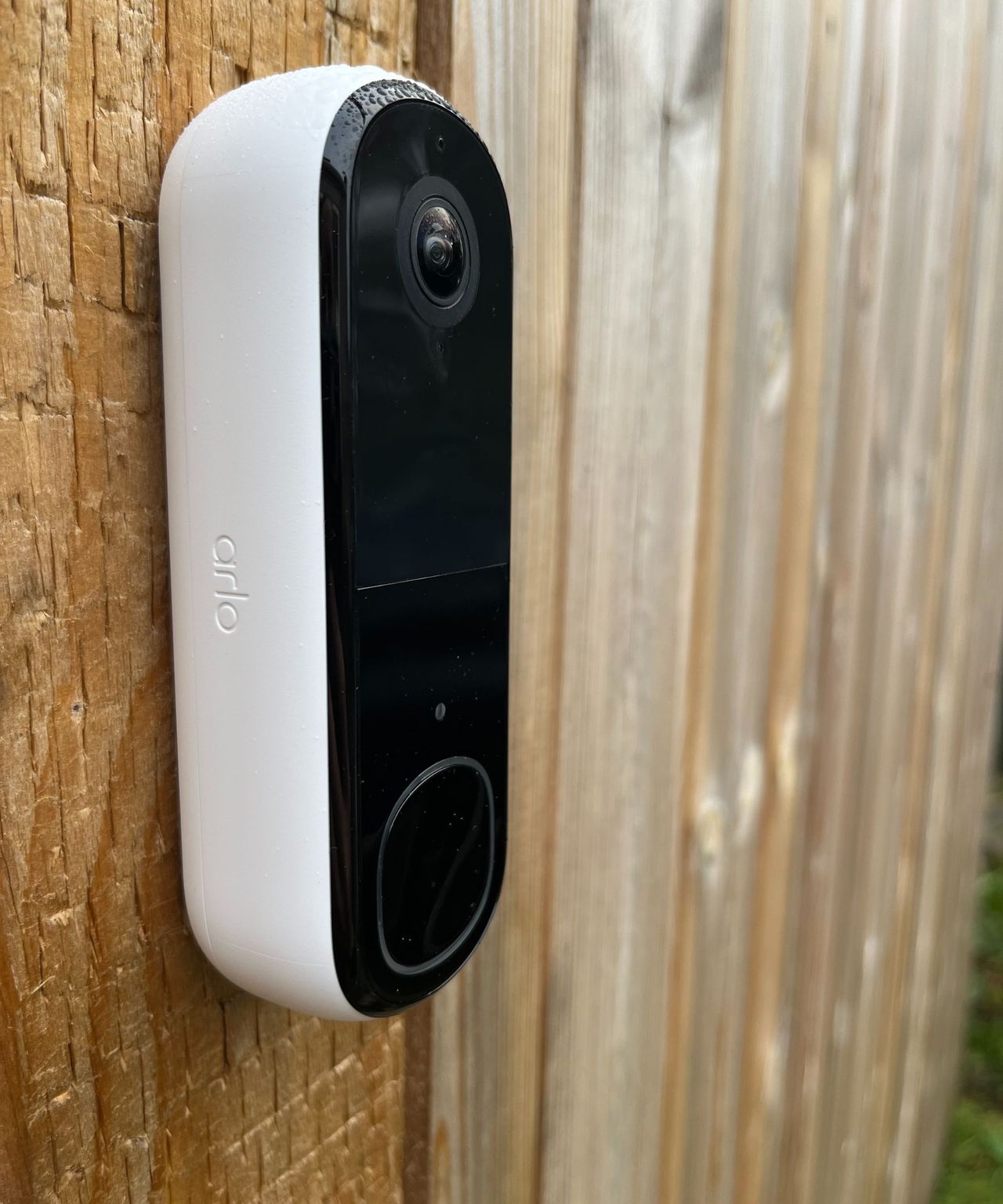 Arlo video doorbell mounted on wooden fence.