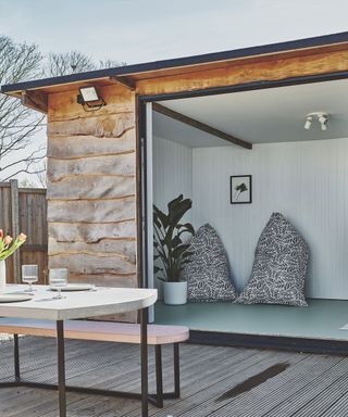 Garden room yoga studio sanctuary, with white paneled walls, mint floor, potted houseplant, and mono bean bags.