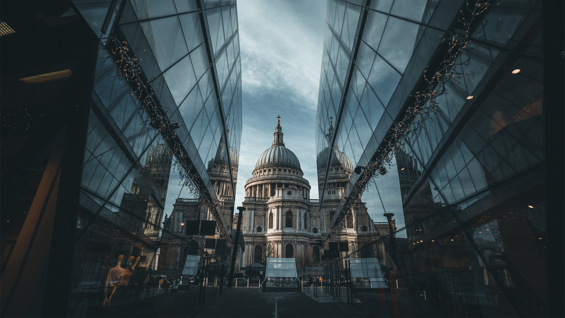 A photo of two glass office buildings on either side of a road with a view of St Paul's Cathedral, London, framed between them at the end