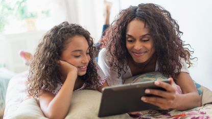 USA, New Jersey, Jersey City, Mother with daughter (8-9) using digital tablet on bed - stock photo