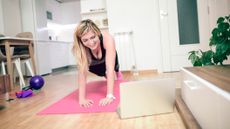 Woman exercising at home in front of a laptop