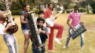 a group of young people hold up instruments outside in a still from the documentary move ya body