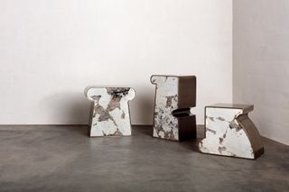 3 side hand-sculptured side tables featuring marble-like design and walnut coloured surfaces. Placed in the corner of a room with white walls and vinyl floor