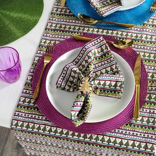 Christmas stripe napkin with gold cutlery and purple placemat on patterned tablecloth