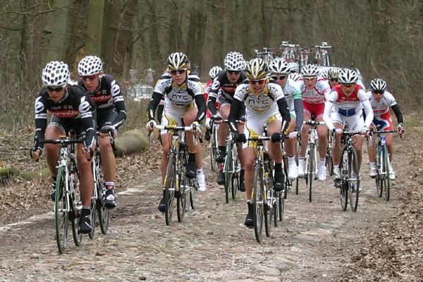 The lead group passes over a cobbled road.