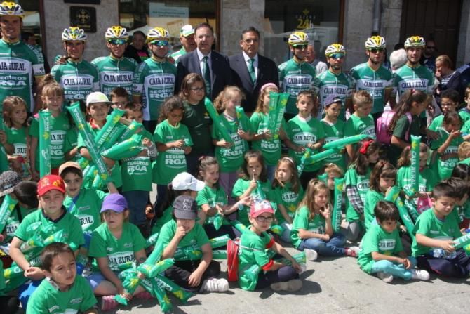 Local children, dressed with Caja Rural shirts, pose with Caja Rural riders before a Caja Rural branch