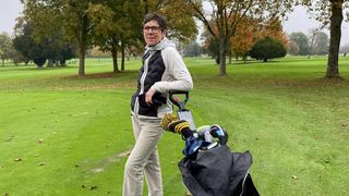 Female golfer leaning against golf trolley