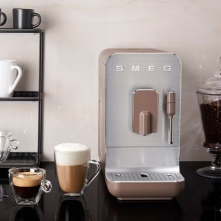 Sleek Smeg coffee machine on a dark kitchen worktop with white wall behind