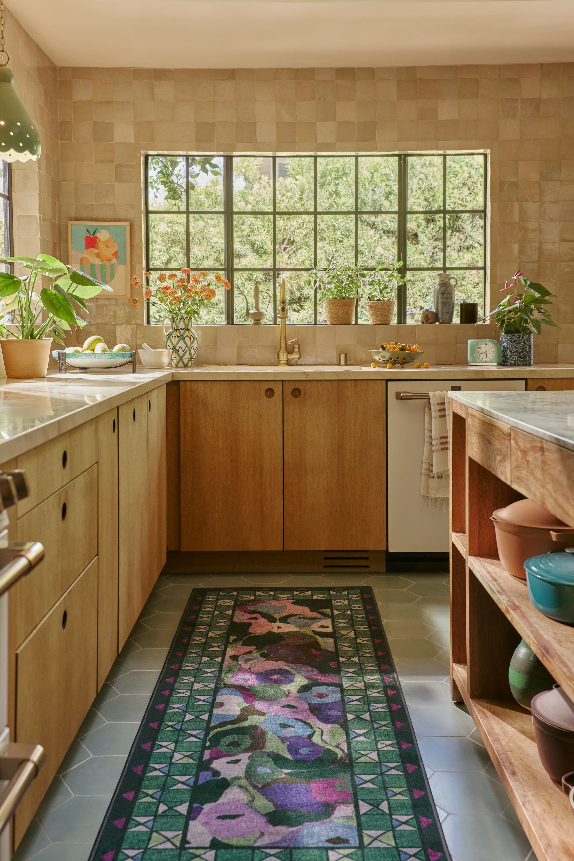 Ruggable x Jungalow&nbsp;collaboration in timber kitchen, with beige zelliege tiles, a green and purple runner, exposed timber kitchen island, gray floor tiles, and potted plants
