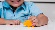 child putting money into piggy bank